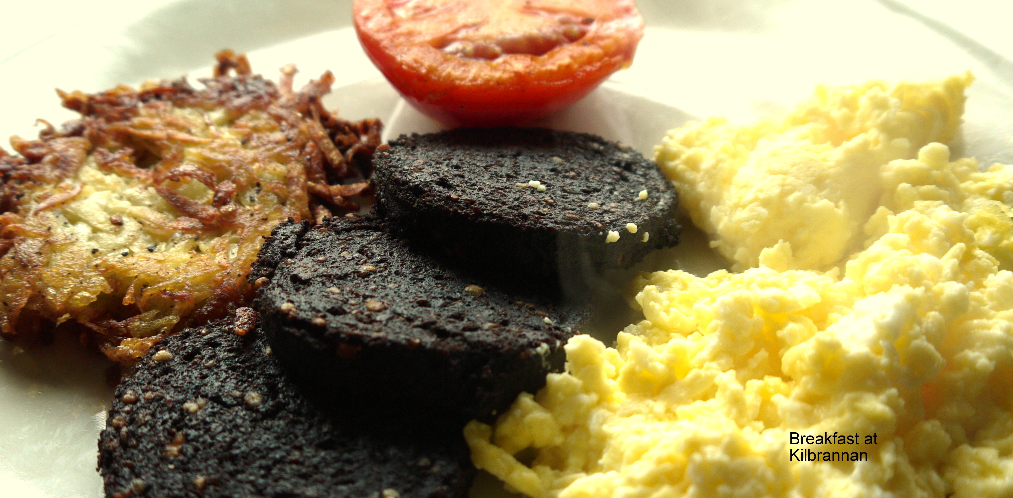 photo of scrambled egg, hash brown, fresh tomato and black pudding